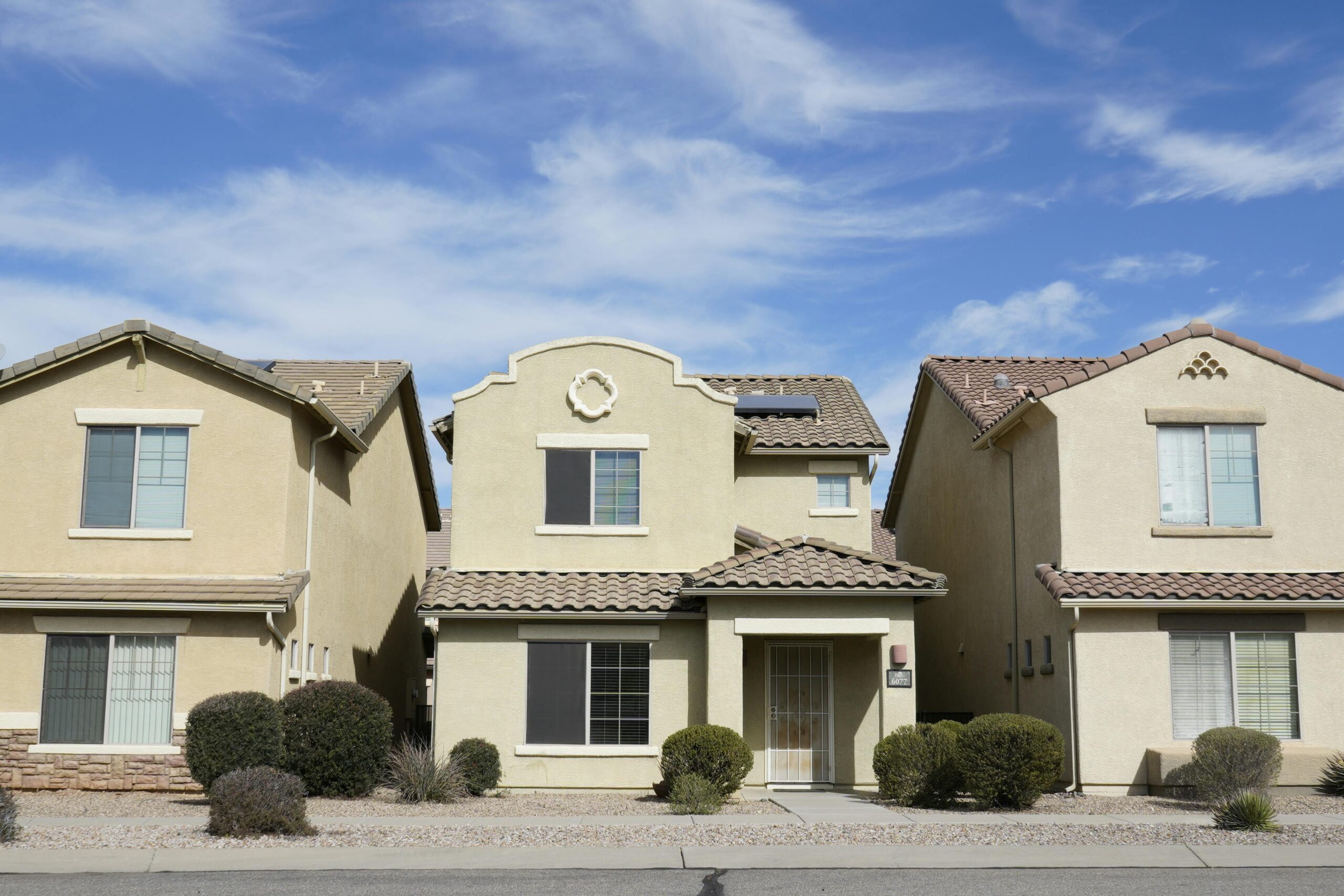 Three adjacent houses in a suburban neighborhood of Tucson, Arizona under a clear sky.