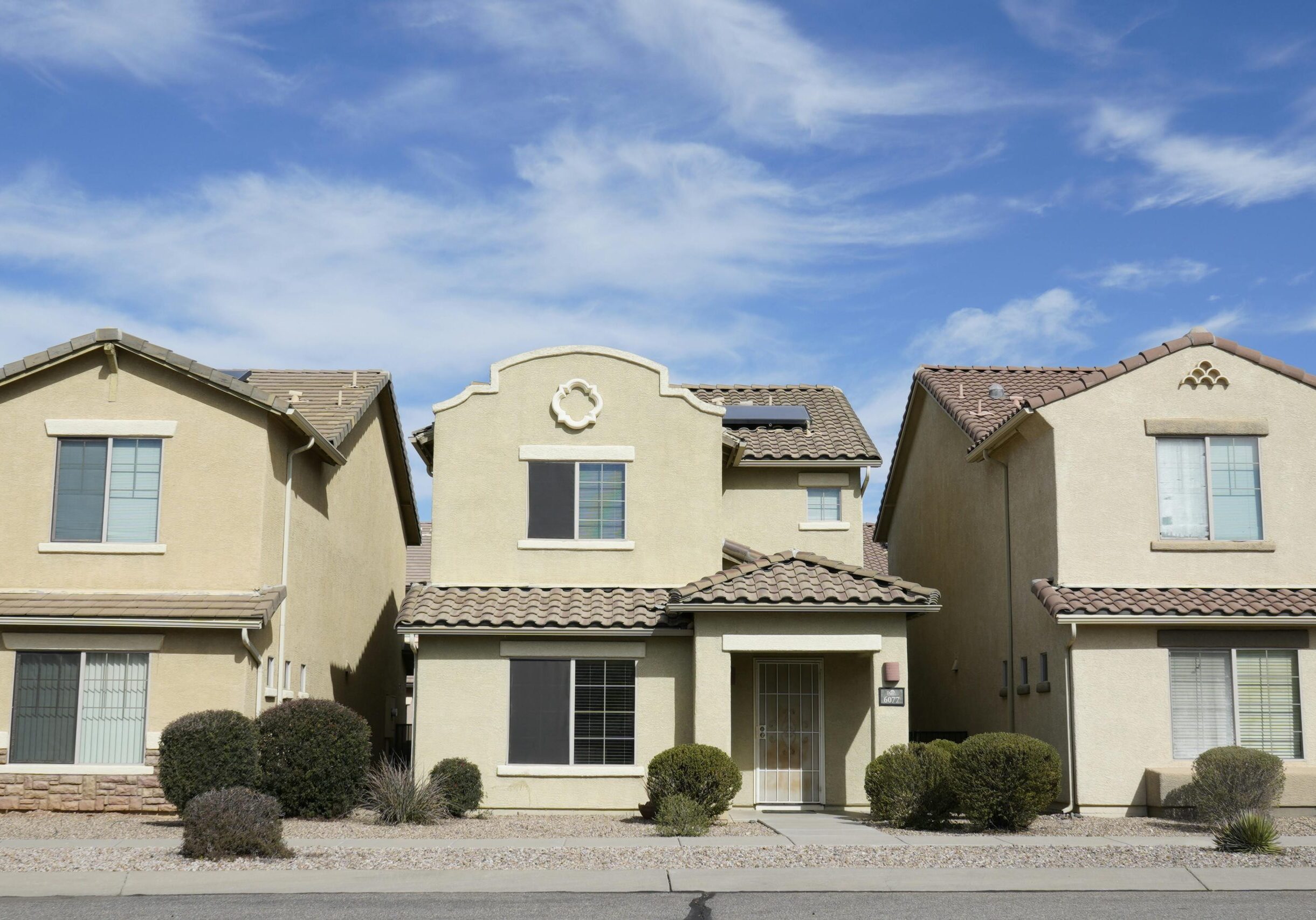 Three adjacent houses in a suburban neighborhood of Tucson, Arizona under a clear sky.