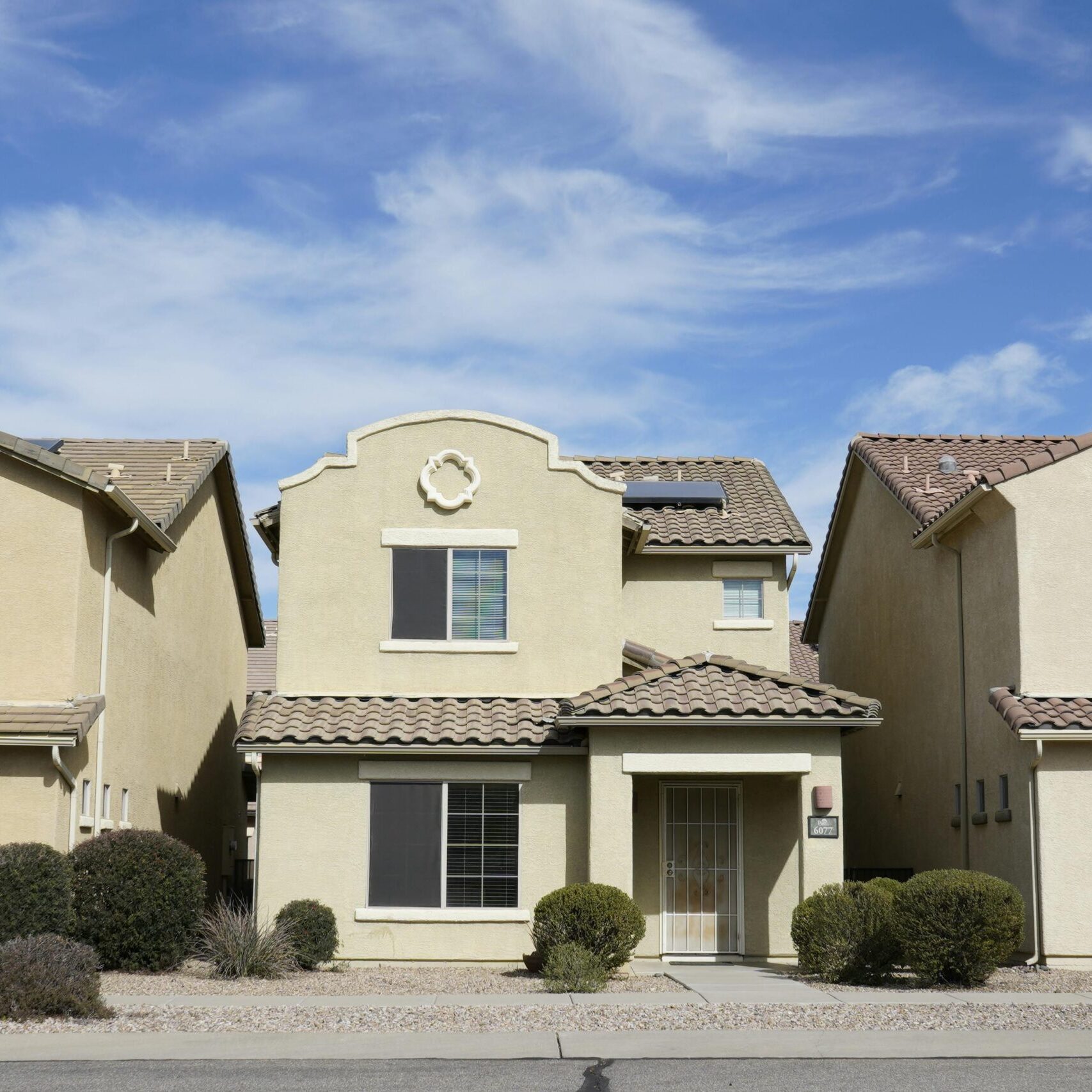 Three adjacent houses in a suburban neighborhood of Tucson, Arizona under a clear sky.