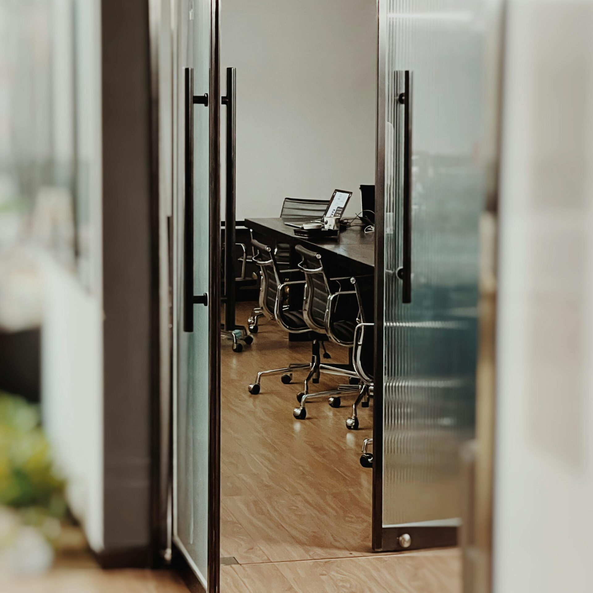 A stylish conference room featuring open glass doors and sleek furniture for a professional setting.